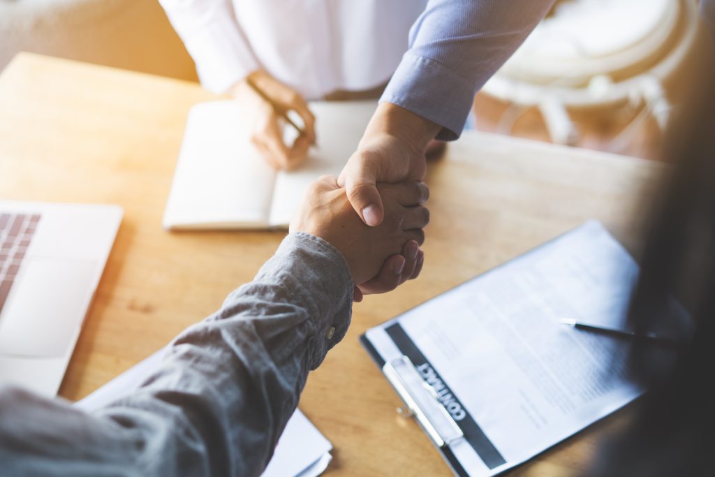 Two businessmen handshaking in meeting after final project agreement deal done.